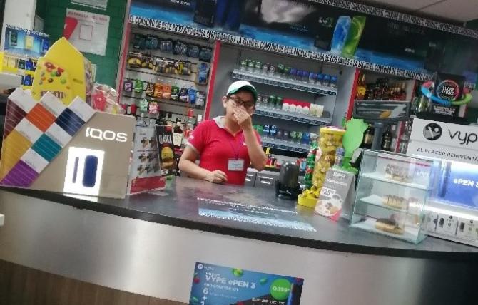 Worker at counter of Guatemalan convenience store selling tobacco products